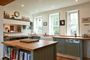Una cocina con una isla de madera, electrodomésticos integrados y vistas al exterior a través de amplias ventanas.