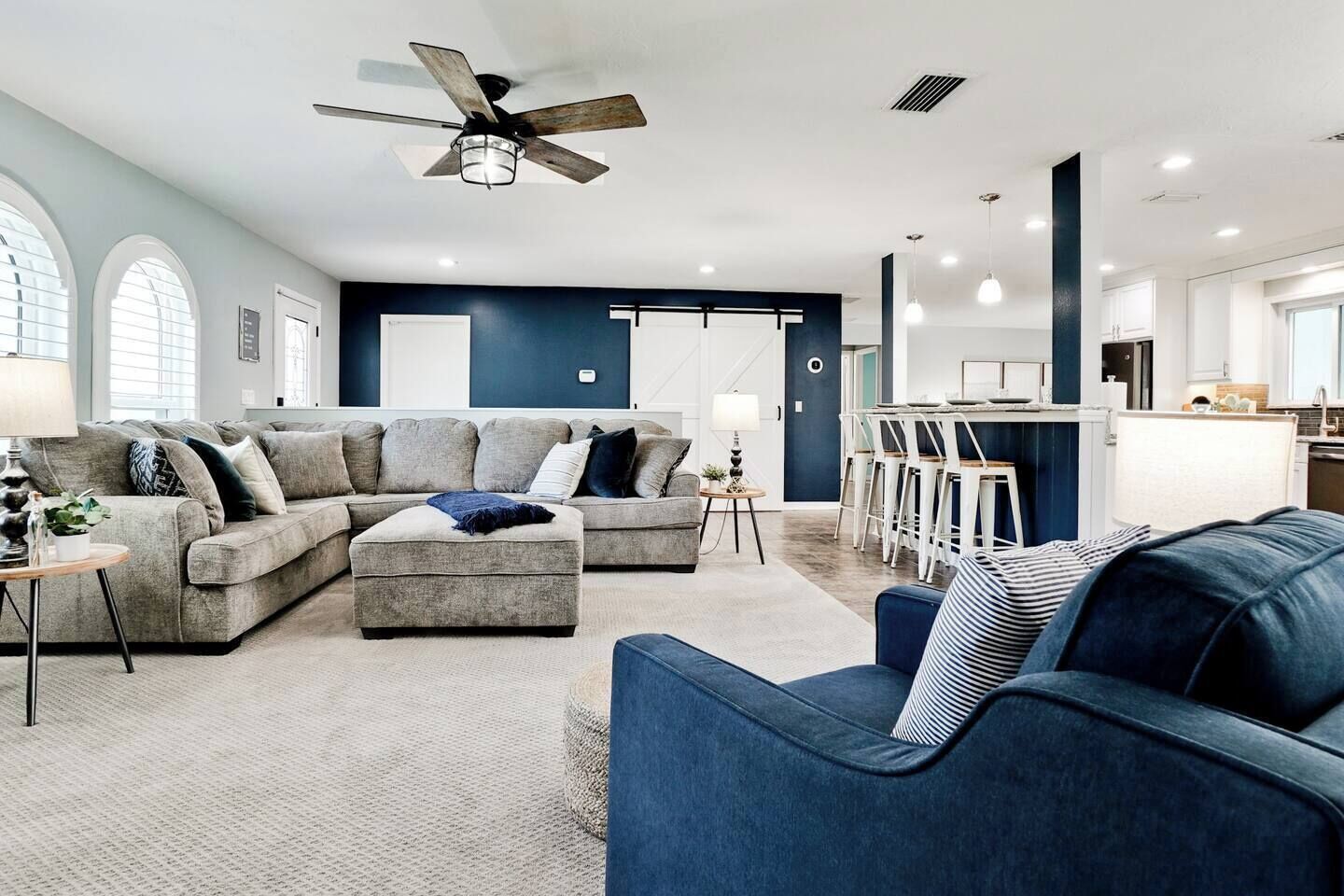 A modern living room with a sectional sofa, ottoman, and a blue armchair.