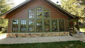 A wooden cabin with a stone foundation, large windows, and a sloped roof.