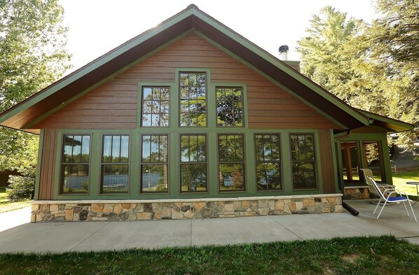 A wooden cabin with a stone foundation, large windows, and a sloped roof.