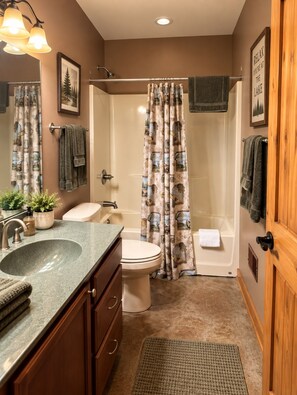 A bathroom with a sink, toilet, bathtub, and shower curtain.