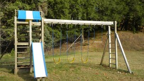 A playground with a slide, swings, and a ladder.