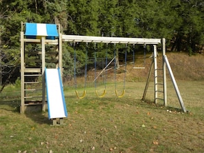 A playground with a slide, swings, and a ladder.