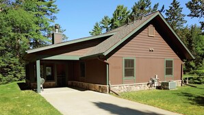 A single-story building with a sloped roof, a covered porch, and a stone foundation.