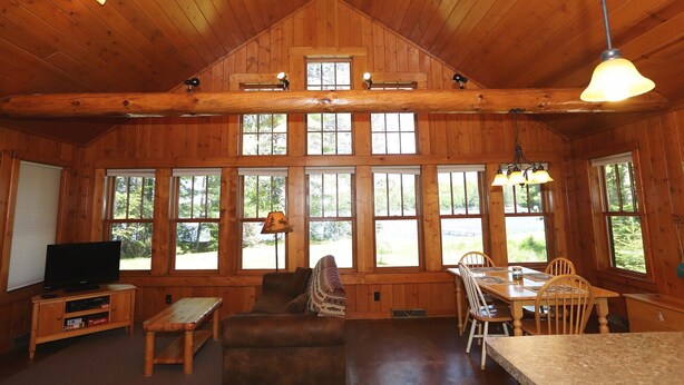 A spacious cabin with a high ceiling, large windows, a cozy seating area, and a dining table.