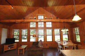 A spacious cabin with a high ceiling, large windows, a cozy seating area, and a dining table.