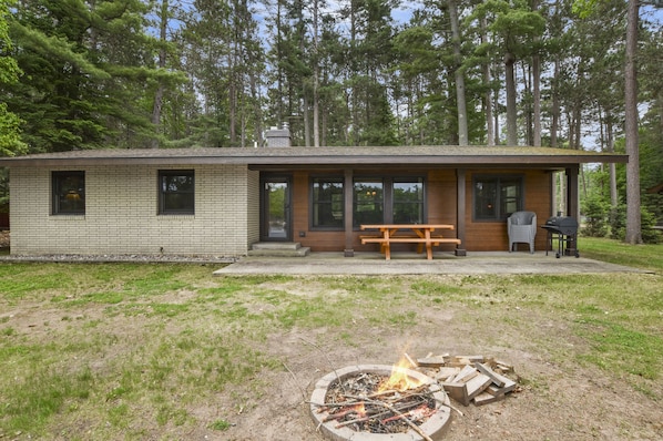 A modern cabin with a fire pit, wooden deck, and a bench. - Uncle Bill's Cabin on Little St Germain Lake (St Germain)
