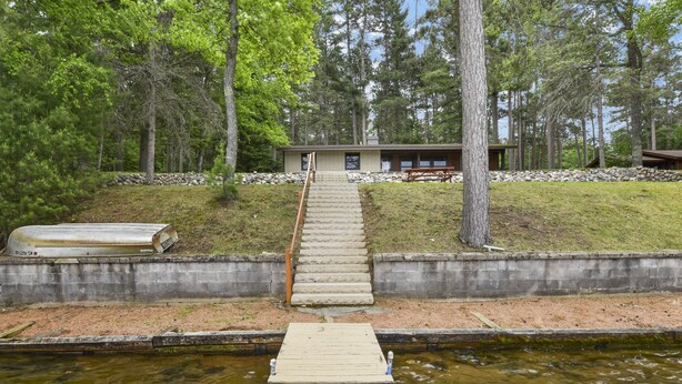 A wooden dock leading to a building surrounded by trees.