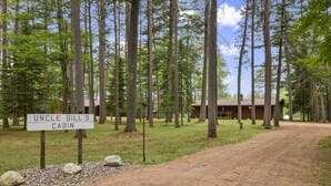A cabin named "Uncle Bill's Cabin" surrounded by tall trees and a dirt path leading to it.