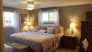 Un dormitorio ordenado con cama, mesitas de noche y un banco.