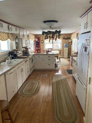 A compact kitchen with white cabinets, a central island, and a refrigerator on the right.