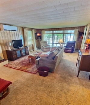 A living room with a sofa, armchairs, a television, and a fireplace.