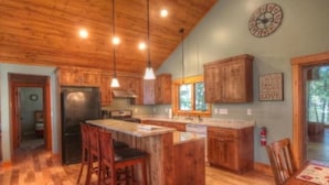 Une cuisine spacieuse avec des meubles en bois, un îlot central et des luminaires suspendus.