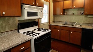 A kitchen with wooden cabinets, a gas stove, a microwave, and a sink. - Liam's Landing located on Little St Germain Lake (St Germain)