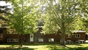 A building with a brick exterior, large windows, and a grassy yard with picnic tables. - Liam's Landing located on Little St Germain Lake (St Germain)