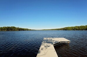 A wooden dock extending into a calm lake with a clear sky above. - Liam's Landing located on Little St Germain Lake (St Germain)
