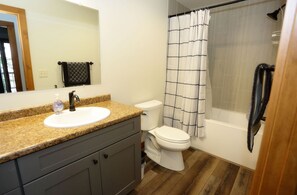 Une salle de bain avec un lavabo sur un plan de travail en granit, des toilettes et une douche avec un rideau.