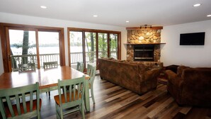 A spacious living area with a stone fireplace, wooden dining table, and comfortable seating. - Eagle Bay on Little St Germain Lake (St Germain)