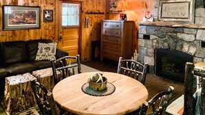 A rustic cabin interior with a wooden dining table, a fireplace, a sofa, and a wall-mounted sign reading "Buckhorn Cabin". - Deer Run Unit #9 on Big St Germain Lake (St Germain)