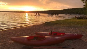 A beach with kayaks and a dock in the background. - Deer Run Unit #9 on Big St Germain Lake (St Germain)