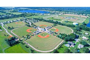 An aerial view of a sports complex with multiple baseball fields, a central building, and surrounding residential areas. - The Perfect Package of Space, Style and Comfort (Auburndale)