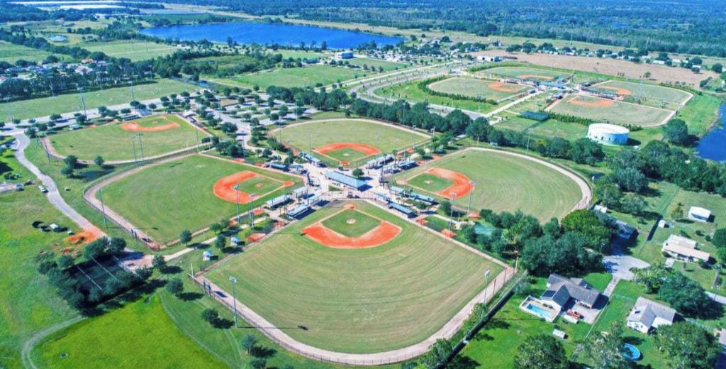 Oversigtsbillede af et sportskompleks med flere baseballbaner, en central bygning og omkringliggende boligområder.
