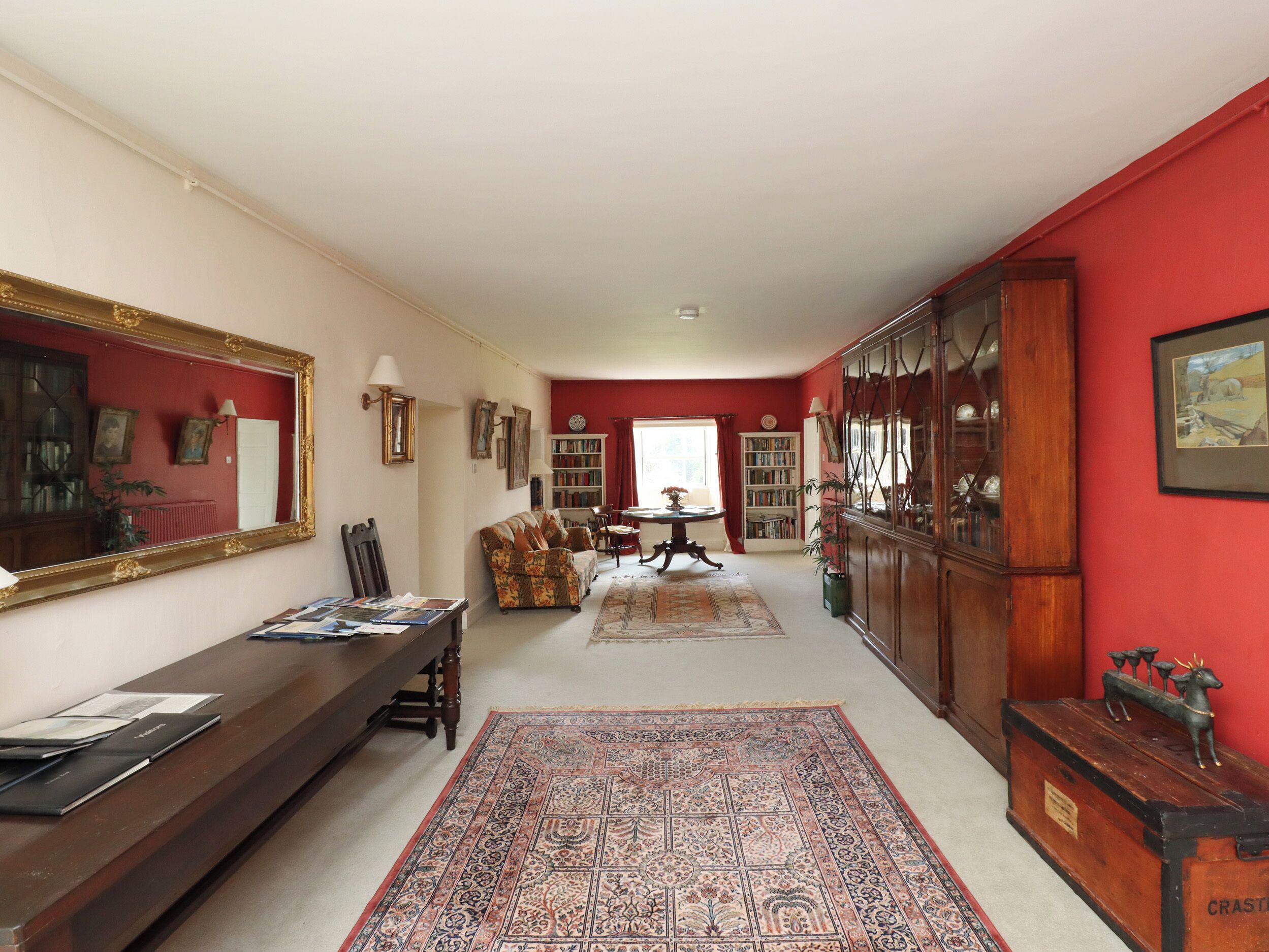 A spacious living room with a large mirror, a sofa, a coffee table, and a bookshelf.