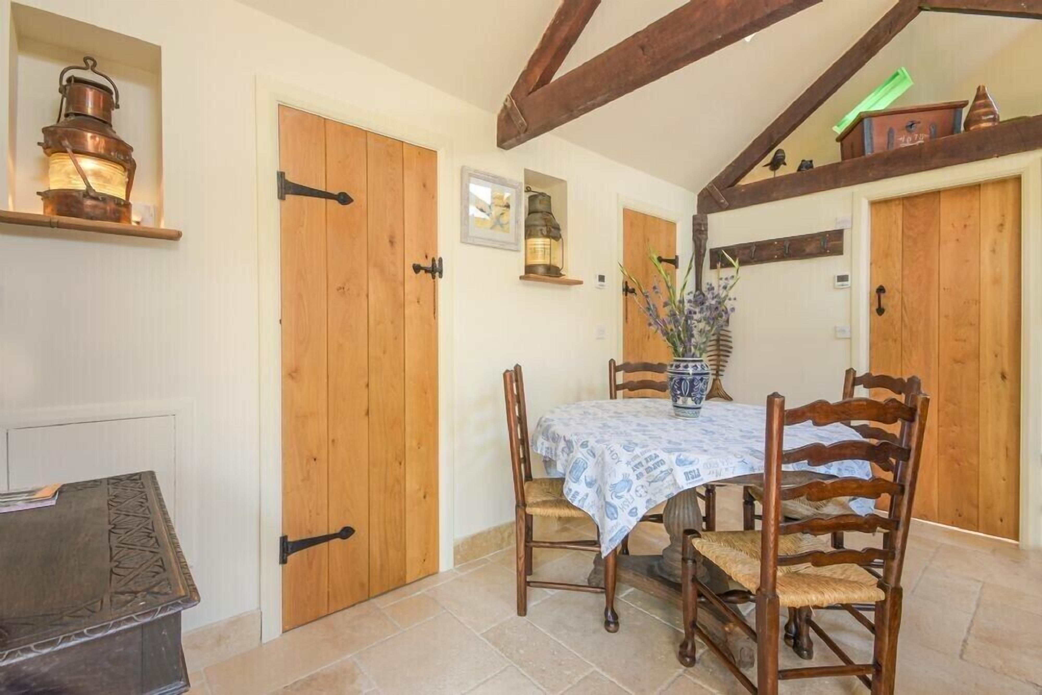 Zona pranzo con porte in legno, un tavolo con tovaglia fantasia e sedie.