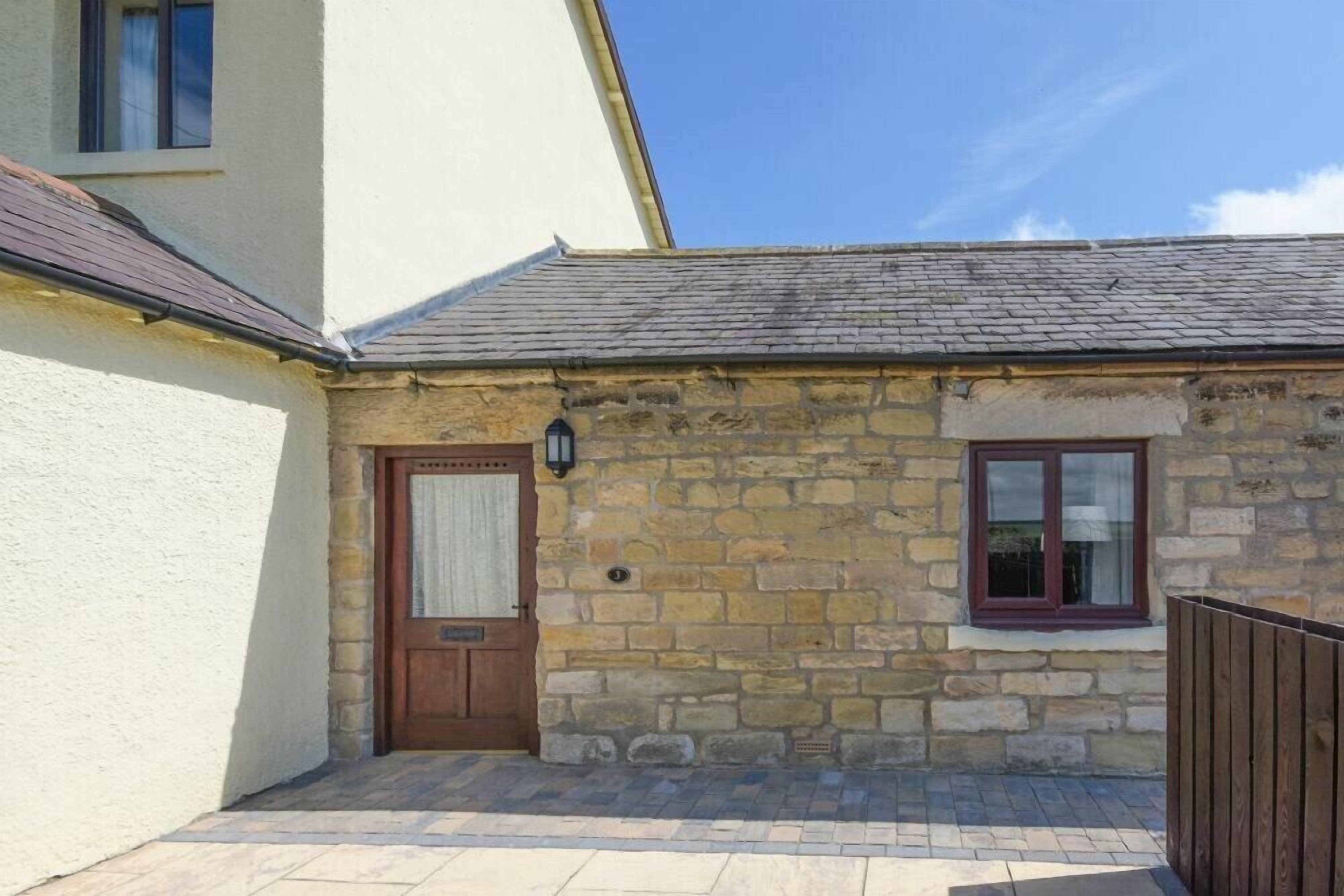 A stone building with a wooden door and window, a small porch area, and a clear blue sky.
