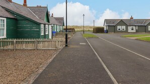 Une rue tranquille bordée de maisons traditionnelles, un ciel dégagé et un lampadaire.
