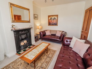 A living room with a fireplace, leather sofa, and a large mirror.
