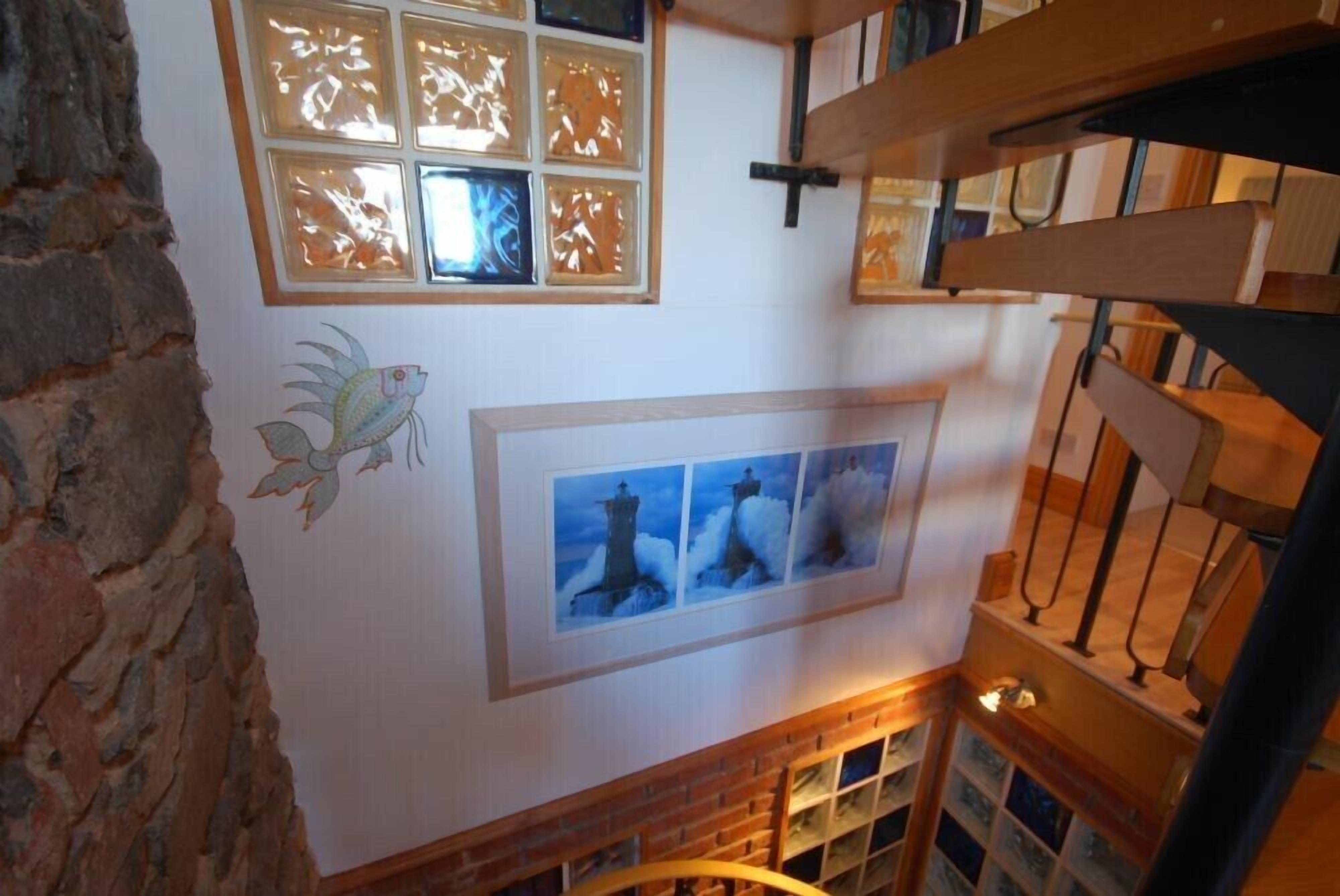 A room with a stone wall, a wooden staircase, and a fireplace.