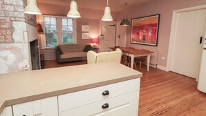 Een gezellige woonkamer met een bank, een eettafel en een keukenhoek met een aanrecht en lades.