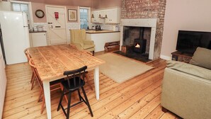 Een gezellige keuken met een houten tafel, stoelen, een haardsteen openhaard en een televisie.