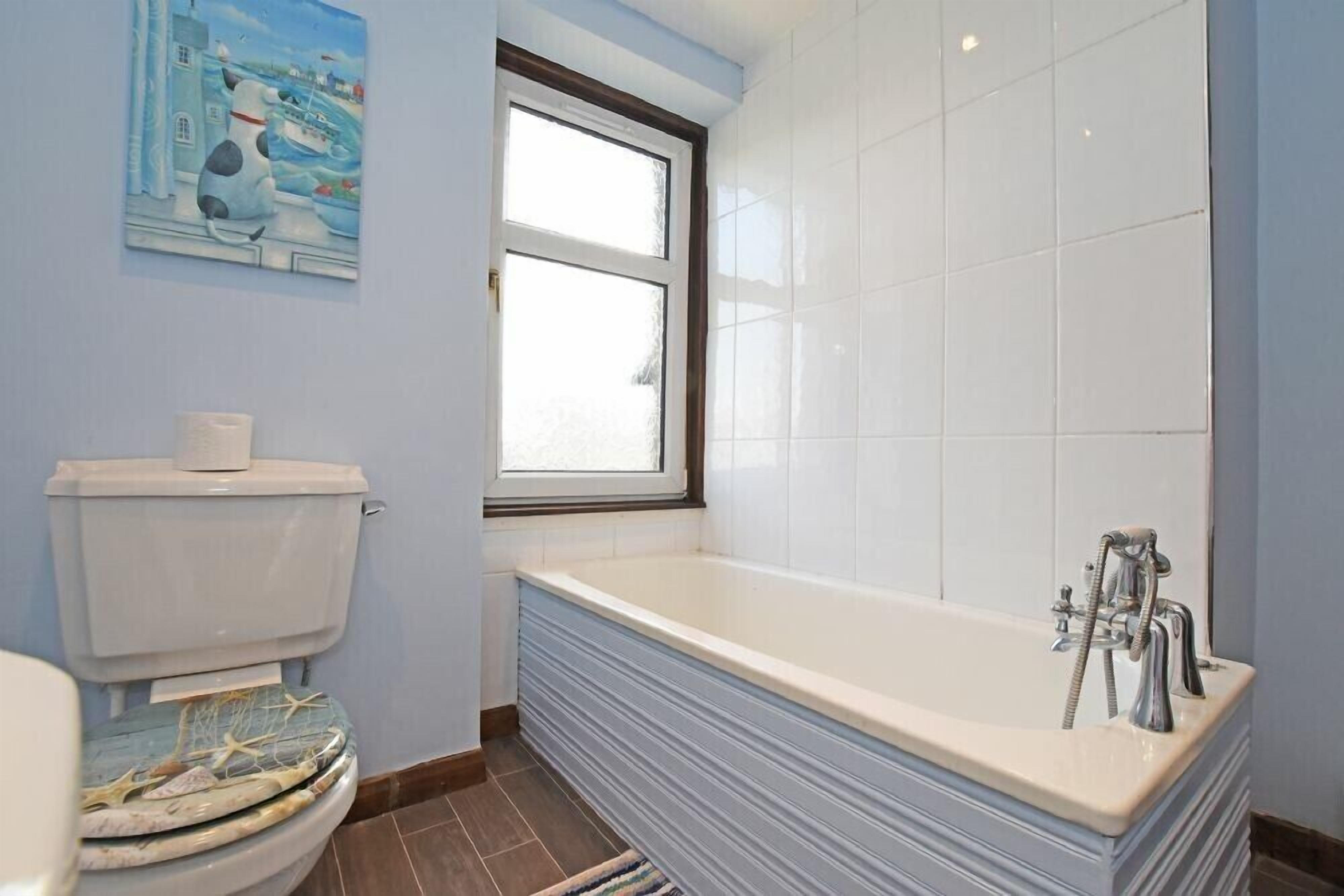 A bathroom with a toilet, a bathtub, and a window.