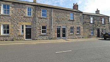 A row of stone buildings with multiple doors and windows, likely residential or small commercial properties.