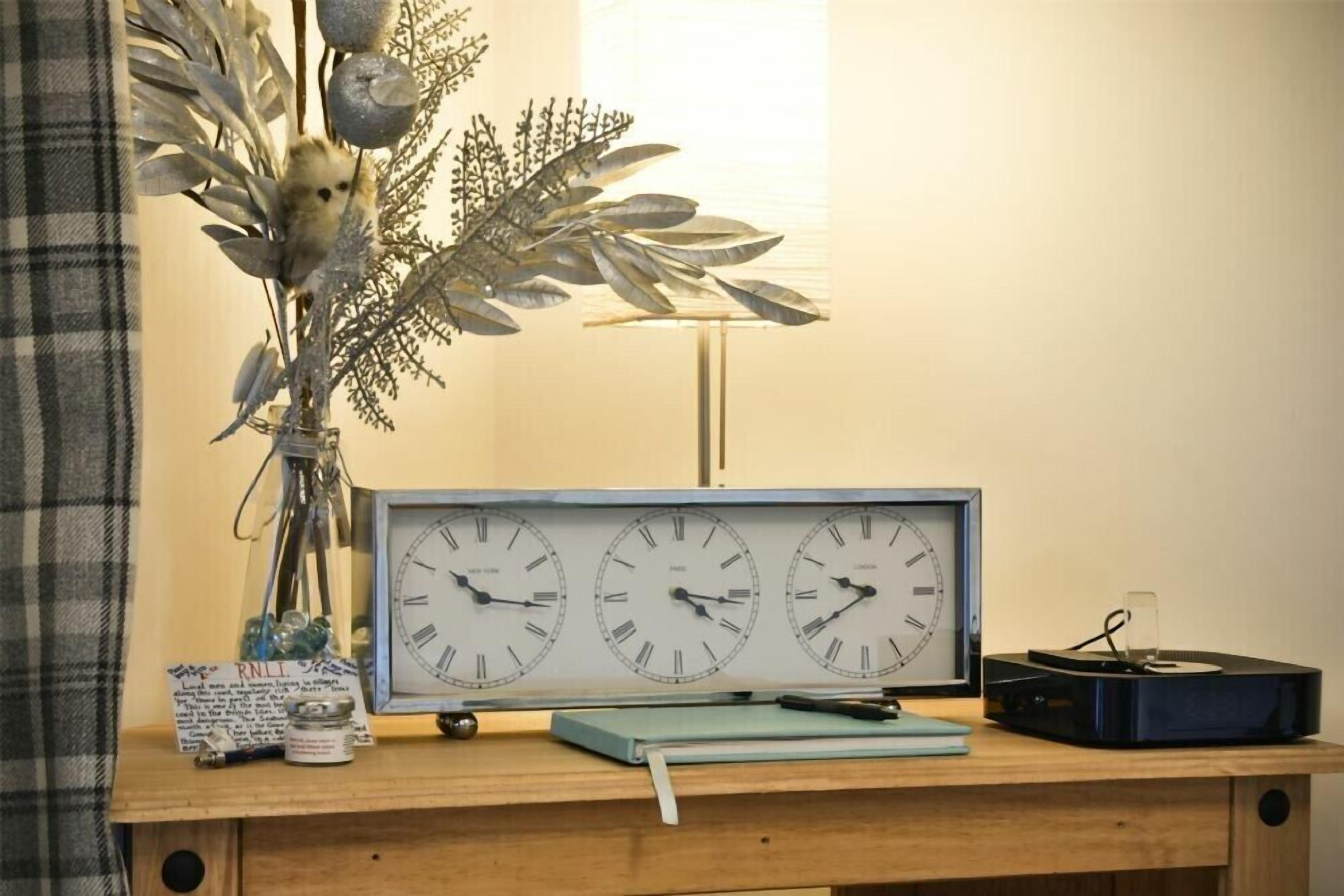 Un bureau en bois, une horloge ancienne, un carnet et une plante.
