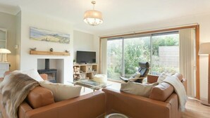 A spacious living room with a large window, a fireplace, a television, and a comfortable seating area. - Spuggies Rest (Alnwick)
