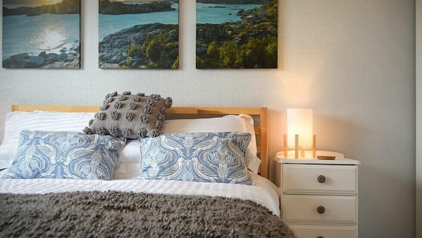 A bedroom with a bed, a nightstand, and three landscape paintings on the wall. - Spuggies Rest (Alnwick)