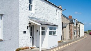 A white building with a small porch and a door, likely a residential property. - Cargoes (Alnwick)
