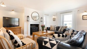 A living room with a fireplace, a television, and a sofa with patterned cushions. - Cargoes (Alnwick)
