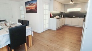 A modern kitchen with white cabinets, a black countertop, and a wooden floor. - Butcher's Retreat (Seahouses)