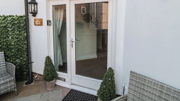 A white building with a glass door, a sign reading "The Butcher's Retreat", and two potted plants. - Butcher's Retreat (Seahouses)