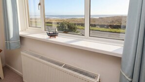 A room with a large window overlooking a coastal landscape. - Dell Point (Chathill)