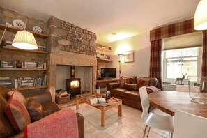 A cozy living room with a stone fireplace, leather sofas, a wooden coffee table, and a television.
