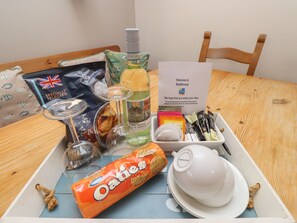 A tray with a bottle of Pinot Grigio, a pack of Oaties, a glass of wine, a cup of coffee, and a welcome card.