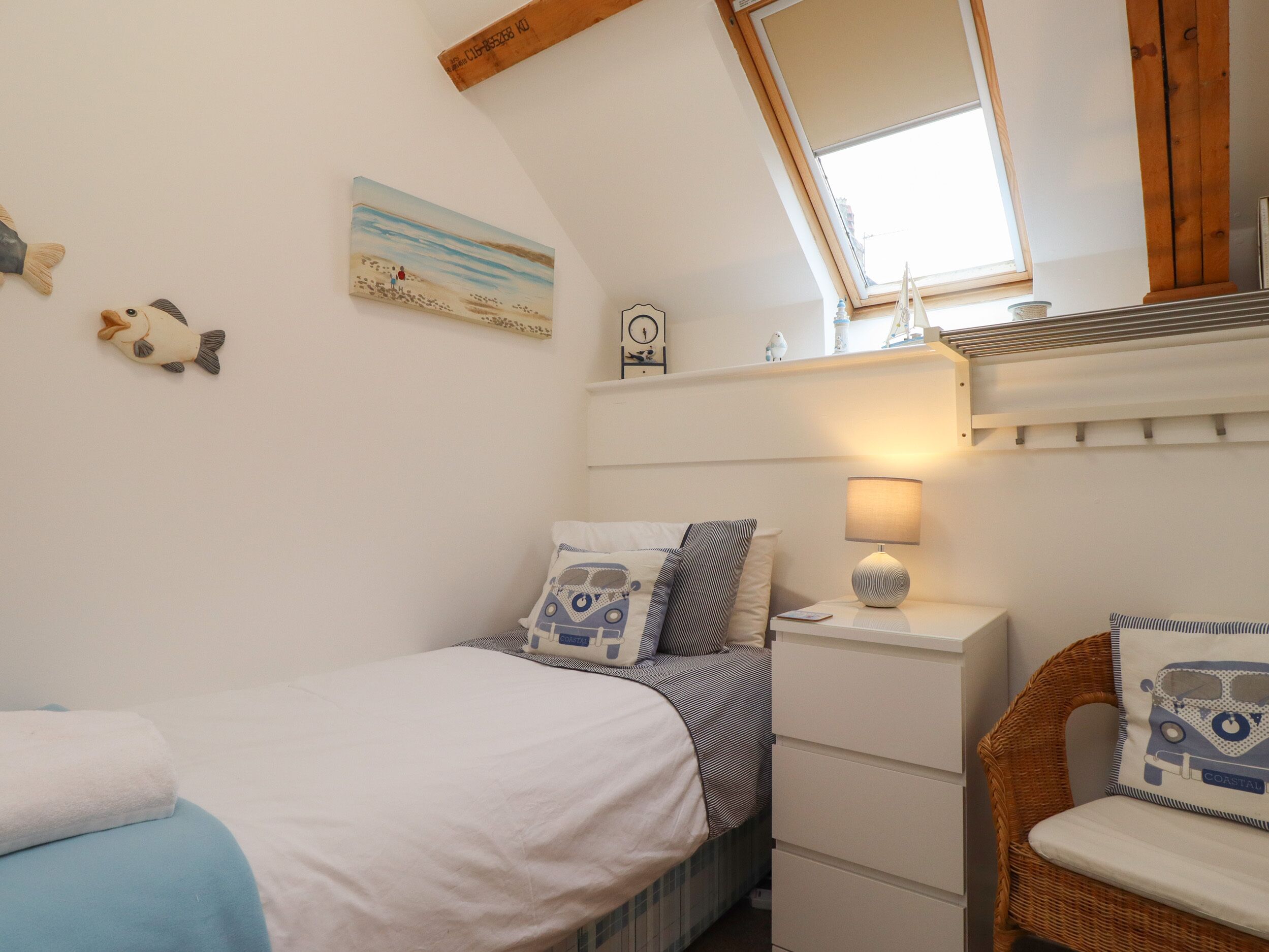 A bedroom with a bed, a chair, a nightstand, a lamp, and a painting on the wall.