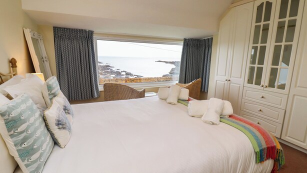 Une chambre avec un grand lit, une vue sur la mer et une armoire aux portes en verre.