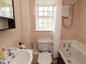 A bathroom with a sink, toilet, bathtub, and a window with a view. - Glebe Cottage (Bamburgh)
