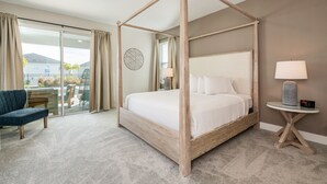 A four-poster bed with a wooden frame, a round wall clock, a small round table with a lamp, and a blue chair. - Encore Luxe 9 BR, Home Theater, Private Pool & Spa (Four Corners)